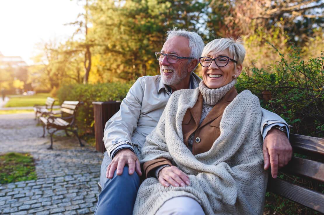 older couple smiling on park bench